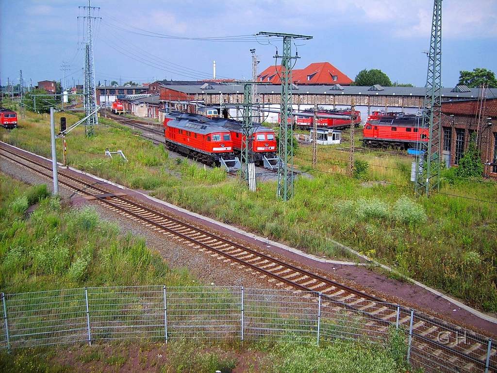 Bw_G_Schuppen2_Berliner-Str.Cargo.006(2).JPG - Blick auf den Schuppen 1. und im Hintergrund auf den Schuppen 2. vom ex. Bw Halle G, heute BD Cargo am 4. Juli 2009. Die Gleise wurden stark zurückgebaut auch im zusammenhang mit den Neubau der Berliner Brücke. Unterhalb vom Fotostandpunkt ist heute ein Damm. Das bedeudet die neue Brücke ist wesentlich kürzer. Denn früher ging die Brücke bis zum Anfang des Lockschuppen 2. Heute hat man hier wie an den neuen Gleis zusehen ist im Straßendamm einen Durchlass für ein Gleis für die Bahnhofumfahrung gelassen. Dieses Gleis ist der Rest vom einstigen Südberg des Güterbahnhof Halle und der mehrgleisigen Umfahrung für Güterzüge für den Hauptbahnhof Halle. Auch die im Bild sichtbaren Prellböcke wurden mit den Rückbau aufgestellt. Denn von den Gleisen gab es eine direckte Einbindung zum Güterbahnhof. Diese ist jetzt nur noch über Hg 1 in der anderen Richtung vorhanden.